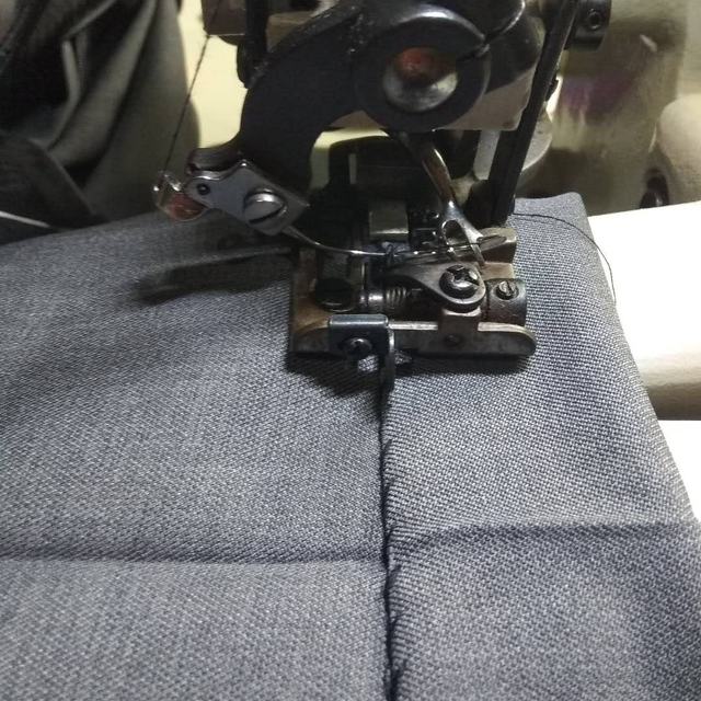 Sewing machine stitching grey fabric